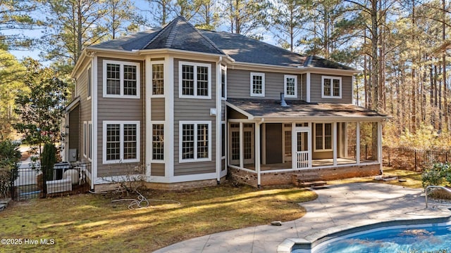 rear view of house featuring a sunroom, a patio area, a fenced in pool, and a yard