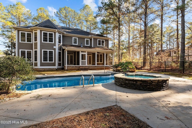 rear view of property featuring a patio area, a sunroom, and a pool with hot tub