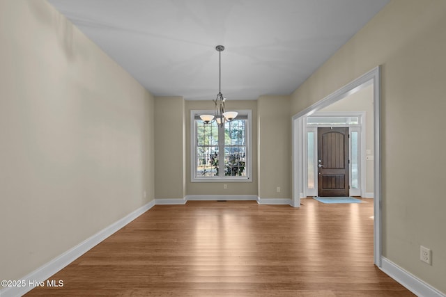 unfurnished dining area with hardwood / wood-style floors and a chandelier