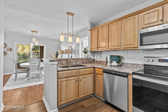 kitchen featuring sink, hanging light fixtures, dark hardwood / wood-style floors, kitchen peninsula, and appliances with stainless steel finishes