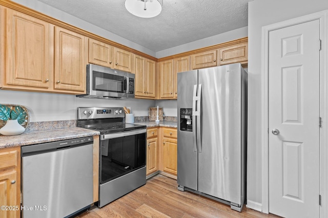 kitchen featuring a textured ceiling, stainless steel appliances, light brown cabinetry, and light hardwood / wood-style flooring