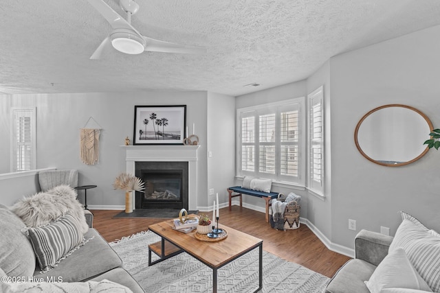 living room featuring a textured ceiling, hardwood / wood-style flooring, and ceiling fan