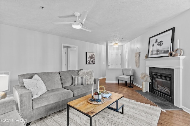 living room featuring hardwood / wood-style floors, ceiling fan, and a textured ceiling