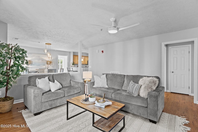 living room with a textured ceiling, light hardwood / wood-style floors, and ceiling fan