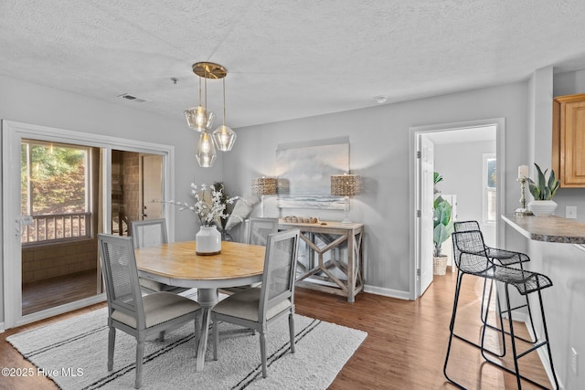 dining area featuring light hardwood / wood-style flooring and a textured ceiling