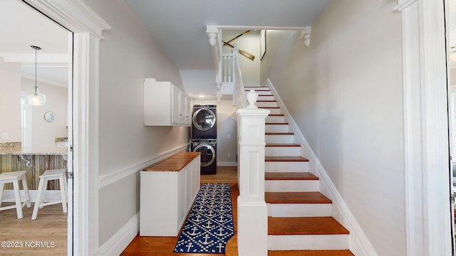 stairs featuring hardwood / wood-style floors and stacked washing maching and dryer