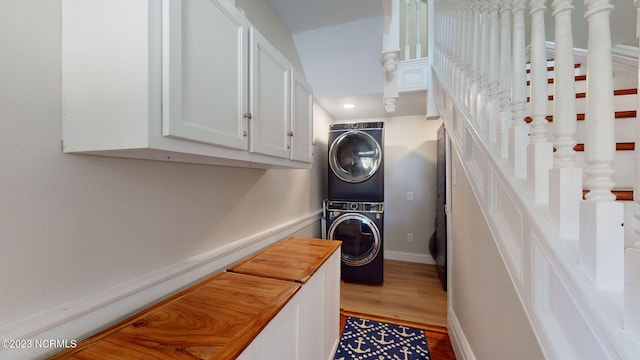 laundry room with light hardwood / wood-style floors and stacked washer and clothes dryer