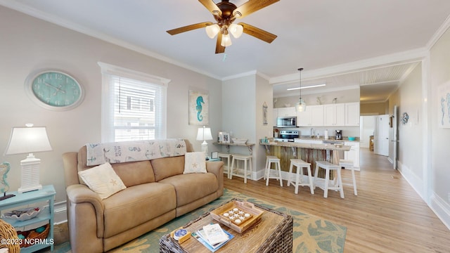 living room featuring ceiling fan, light hardwood / wood-style flooring, sink, and ornamental molding