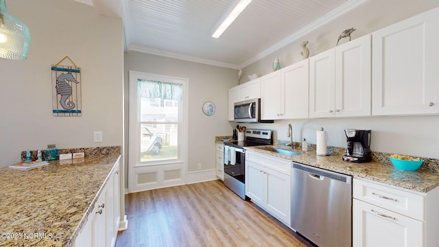 kitchen with stainless steel appliances, white cabinetry, ornamental molding, and sink