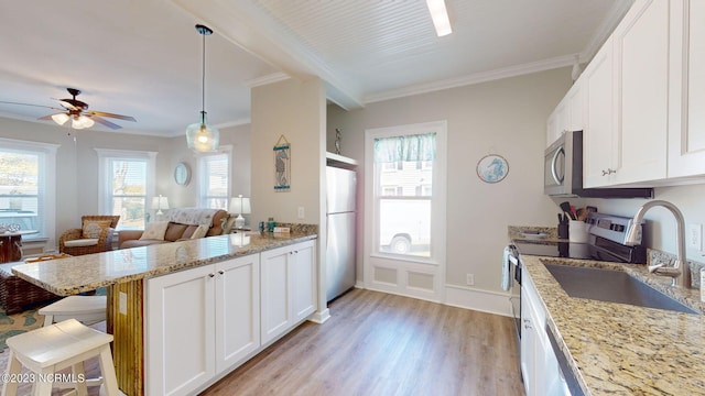 kitchen with light wood-type flooring, light stone counters, appliances with stainless steel finishes, a kitchen bar, and white cabinetry