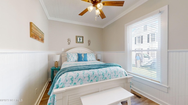 bedroom with hardwood / wood-style floors, ceiling fan, and ornamental molding