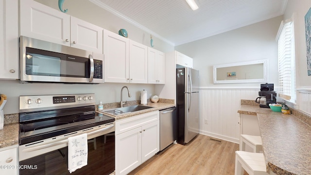 kitchen with sink, light hardwood / wood-style flooring, crown molding, white cabinets, and appliances with stainless steel finishes