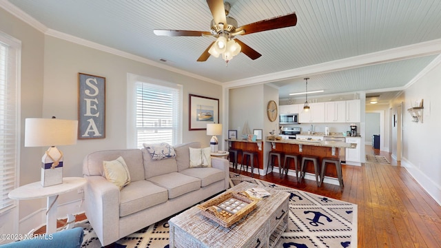 living room featuring ceiling fan, ornamental molding, and light hardwood / wood-style flooring