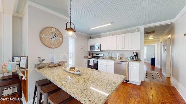 kitchen with white cabinets, crown molding, hanging light fixtures, light stone countertops, and appliances with stainless steel finishes