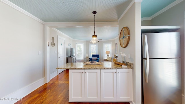 kitchen with light stone countertops, ceiling fan, hanging light fixtures, stainless steel fridge, and white cabinets