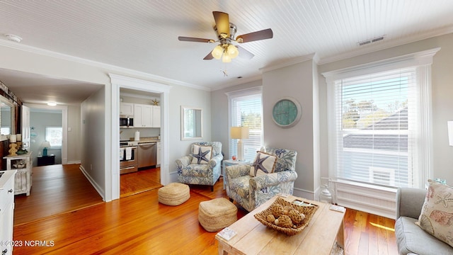 living room with hardwood / wood-style floors, ceiling fan, ornamental molding, and a wealth of natural light