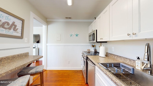 kitchen with white cabinets, light hardwood / wood-style floors, sink, and stainless steel appliances