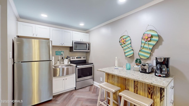 kitchen with light stone countertops, white cabinetry, light parquet flooring, and stainless steel appliances