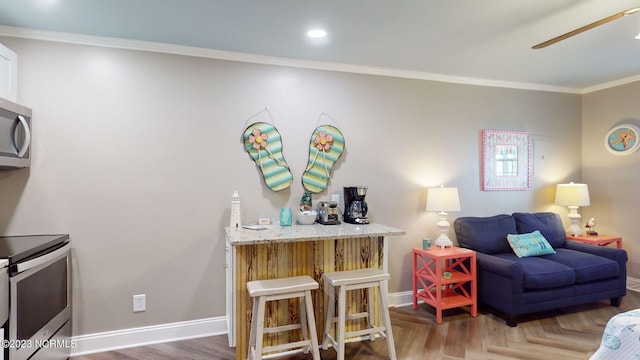 living room with indoor bar, dark parquet floors, ceiling fan, and ornamental molding