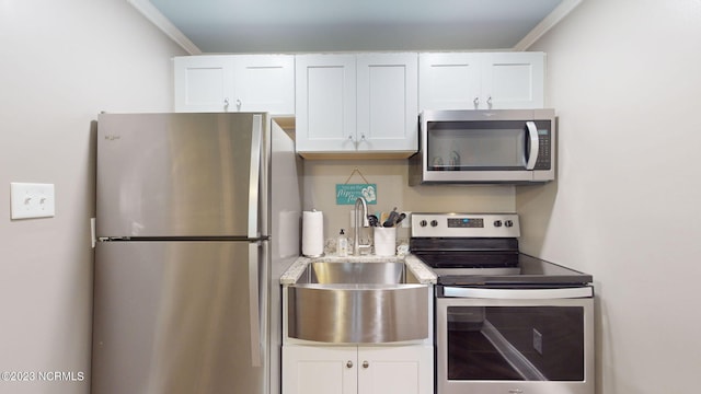 kitchen with white cabinets, appliances with stainless steel finishes, crown molding, and sink