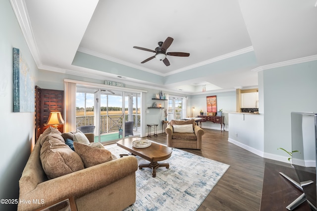 living room with a tray ceiling, ceiling fan, crown molding, and dark hardwood / wood-style floors