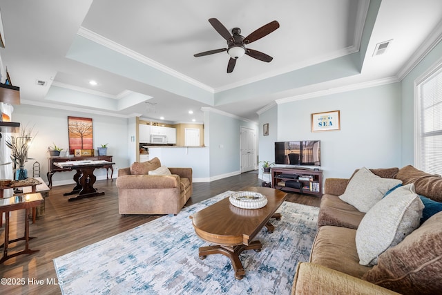 living room with dark hardwood / wood-style flooring, ceiling fan, a raised ceiling, and crown molding