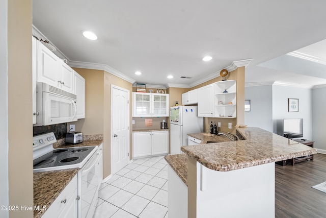 kitchen featuring white cabinetry, kitchen peninsula, dark stone counters, white appliances, and a breakfast bar area