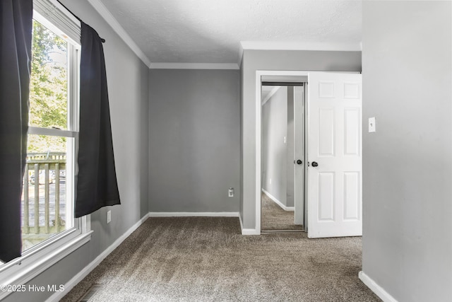 unfurnished bedroom with carpet flooring, a textured ceiling, a closet, and crown molding