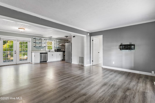 unfurnished living room with dark wood-type flooring, french doors, crown molding, sink, and a textured ceiling