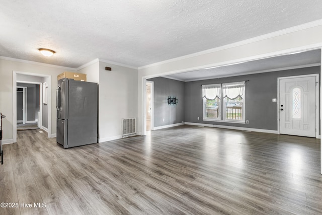 unfurnished living room with light wood-type flooring, a textured ceiling, and crown molding