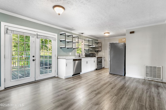 kitchen with sink, stainless steel appliances, crown molding, pendant lighting, and white cabinets