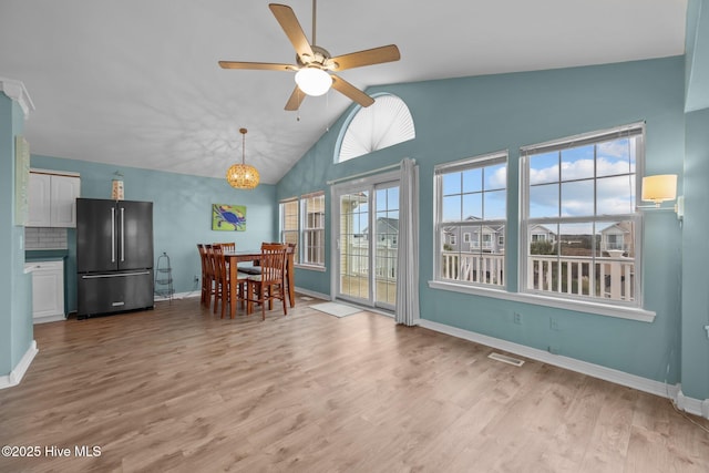 unfurnished dining area featuring ceiling fan with notable chandelier, light hardwood / wood-style flooring, and lofted ceiling