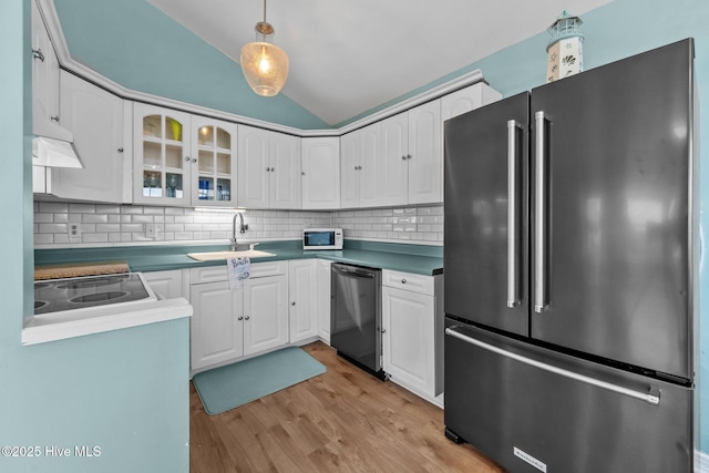 kitchen with decorative backsplash, stainless steel appliances, sink, white cabinets, and lofted ceiling