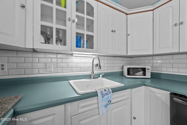 kitchen with decorative backsplash, white cabinetry, sink, and stainless steel dishwasher