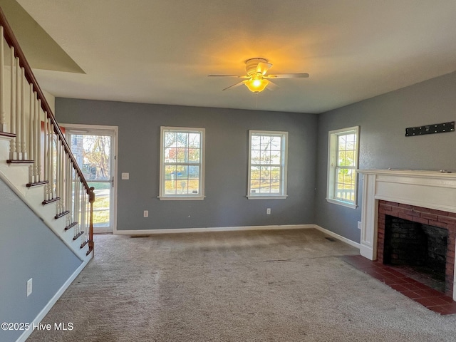 unfurnished living room featuring light carpet, a fireplace, ceiling fan, and a healthy amount of sunlight