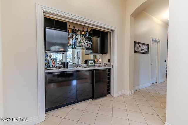 bar featuring sink, refrigerator, and light tile patterned flooring