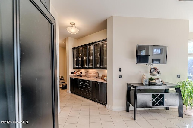 bar featuring dark brown cabinetry and light tile patterned floors