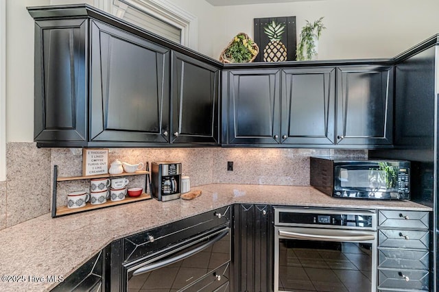 kitchen featuring decorative backsplash, oven, and light stone counters