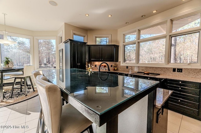 kitchen featuring a wealth of natural light, light tile patterned floors, hanging light fixtures, and a breakfast bar area