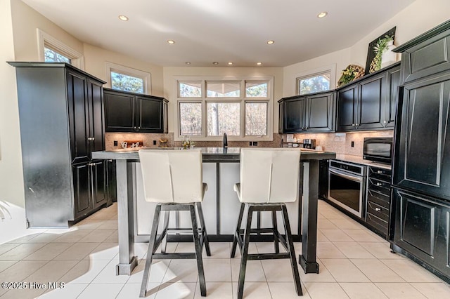 kitchen featuring decorative backsplash, light tile patterned floors, oven, and a kitchen island