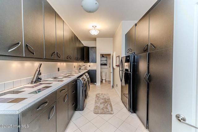 kitchen featuring washer / dryer, light tile patterned floors, and dark brown cabinetry