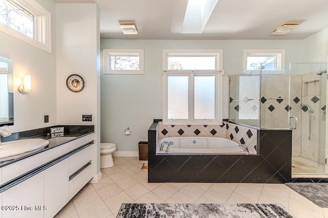 full bathroom with a skylight, vanity, independent shower and bath, tile patterned flooring, and toilet