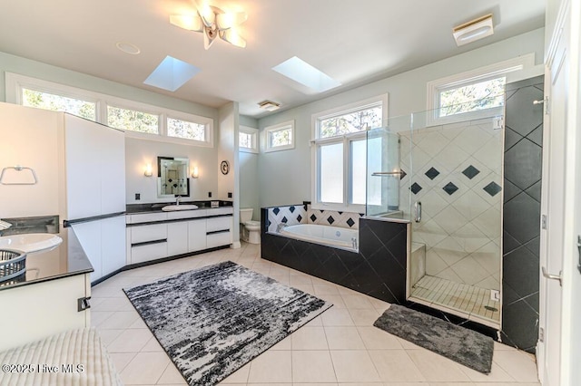 full bathroom featuring a skylight, tile patterned flooring, separate shower and tub, toilet, and vanity