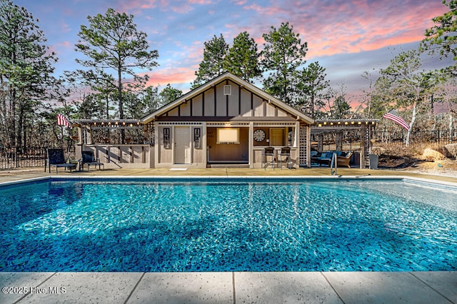 pool at dusk featuring an outbuilding and a patio area