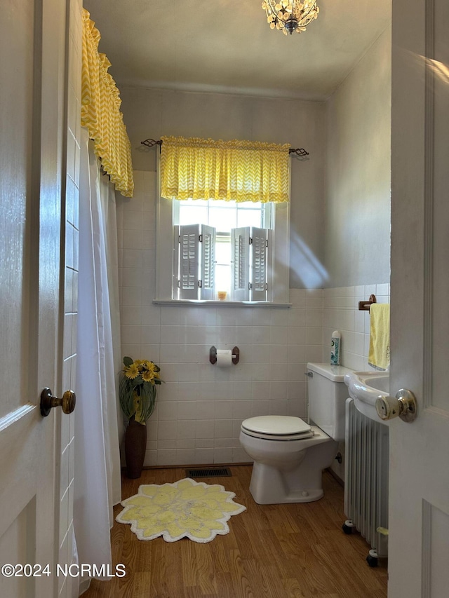 bathroom featuring toilet, wood-type flooring, tile walls, and radiator