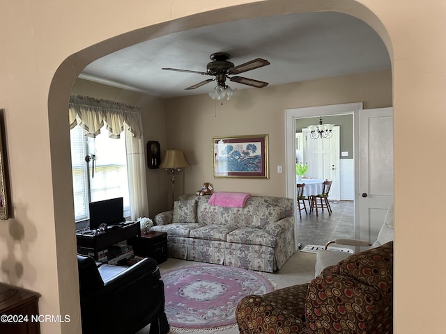 tiled living room featuring ceiling fan with notable chandelier