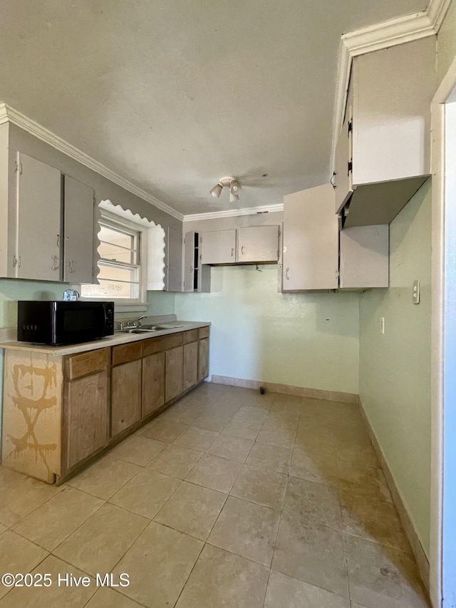 kitchen featuring sink, light tile patterned floors, and ornamental molding