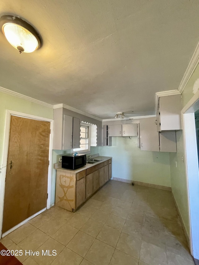 kitchen featuring white cabinetry, crown molding, and sink