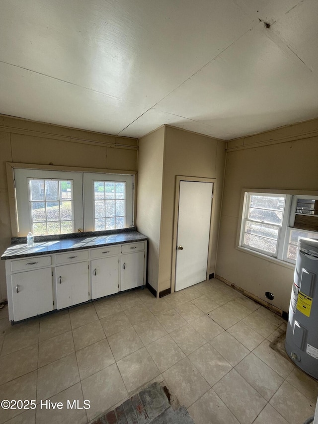 kitchen featuring light tile patterned floors, electric water heater, and white cabinetry