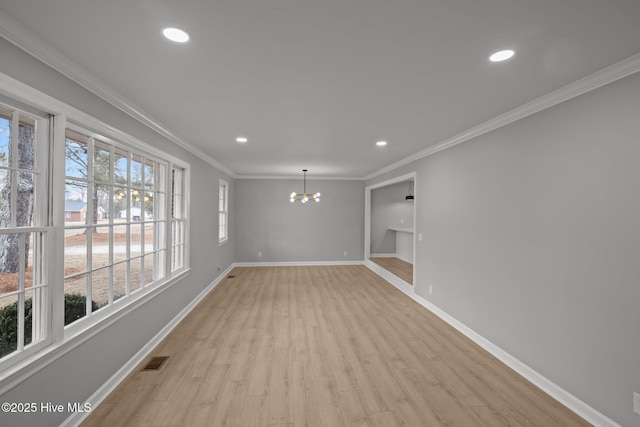 empty room with a chandelier, light hardwood / wood-style flooring, and ornamental molding